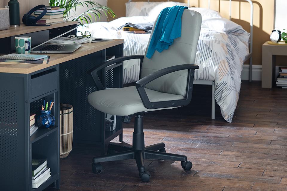 Image of grey and black office chair next to  a desk in a bedroom.