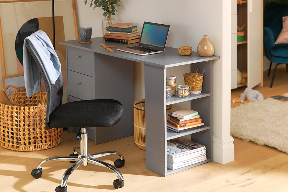 Image of grey desk and black office chair in a bedroom.