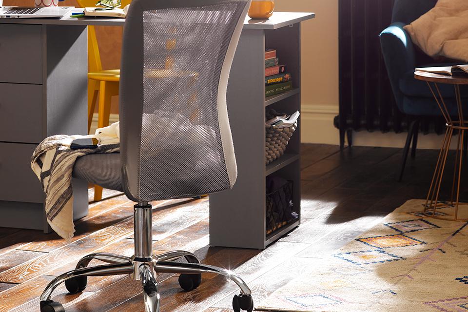 Image of a grey, mesh office chair next to a desk.