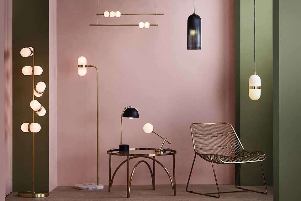 Image of a selection lighting types in gold and black in a pale pink room.