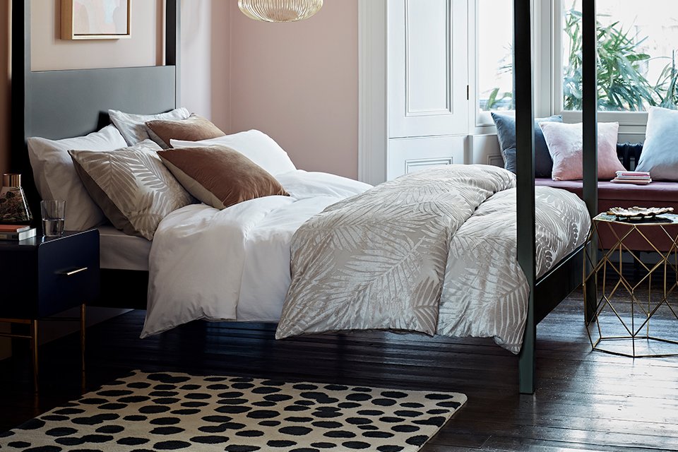Black four poster bed with white bedding in a luxe bedroom.