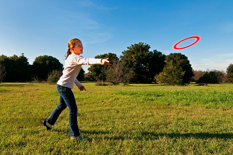 A girl throwing an Aerobie Sprint 10 inch flying ring in a field.
