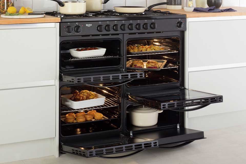 A range cooker with open doors showing lots of food inside and saucepans on top