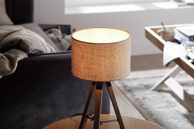Image of a wooden tripod table lamp with a beige, fabric shade.