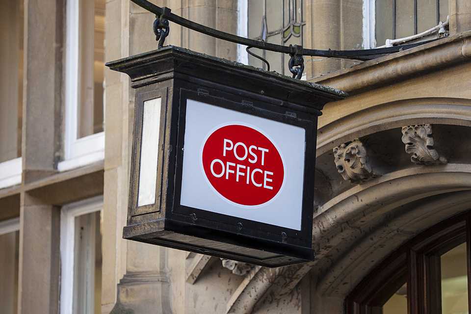 A post office sign outside a building.