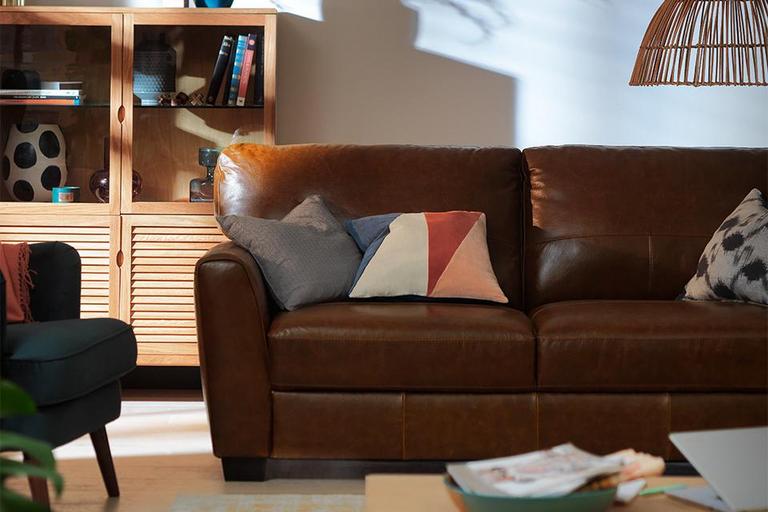 A brown leather sofa with accent cushions.