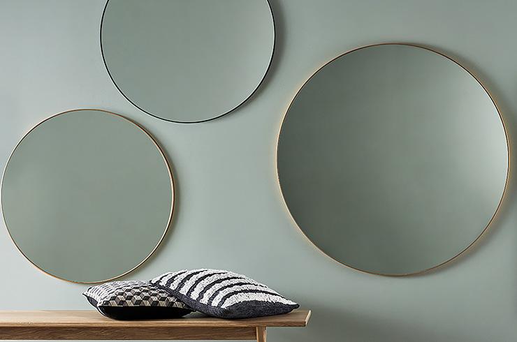 Three round mirrors hanging on the wall in brass and black.