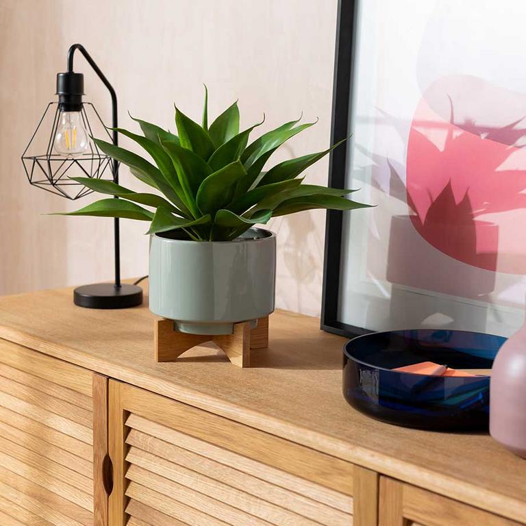 Image of a faux succulent on a wooden sideboard.