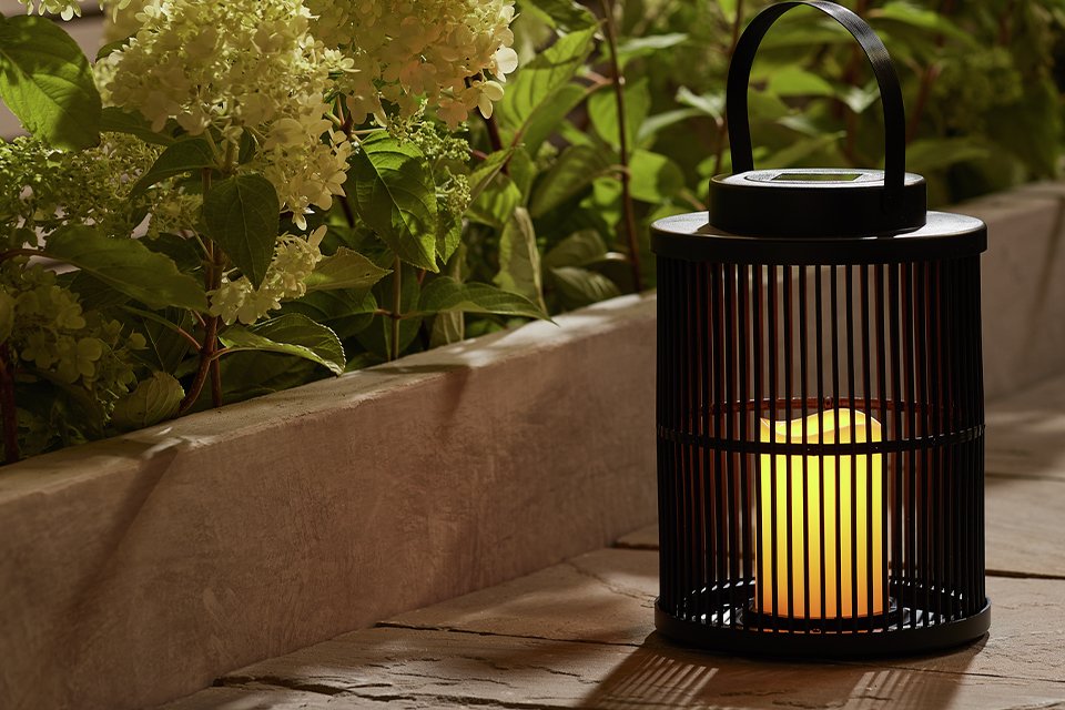 Garden by Sainsbury's solar flickering candle lantern placed outdoors next to a lawn edge.