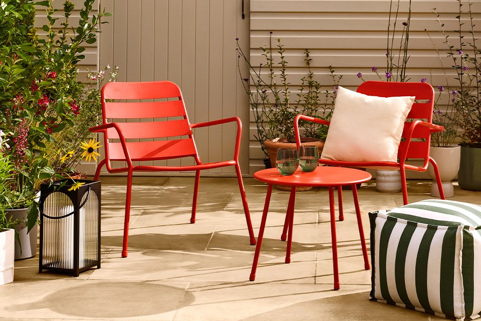 Two red Habitat outdoor metal chairs on a patio.