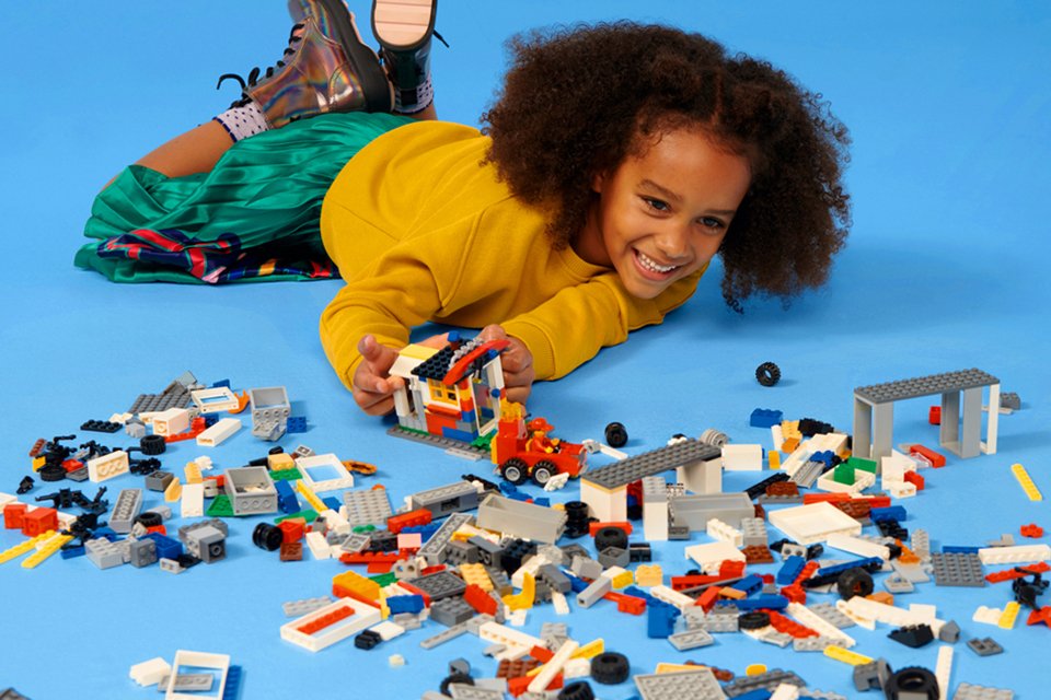 Child playing with LEGO® bricks on a blue background, showcasing creativity and building skills.