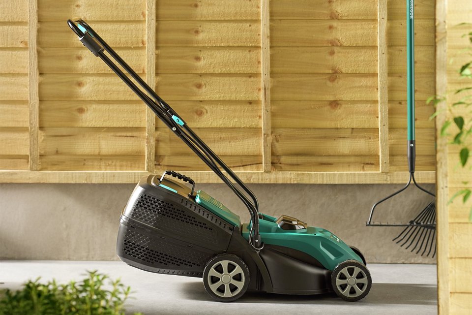 A green McGregor lawnmower displayed against a wooden backdrop.