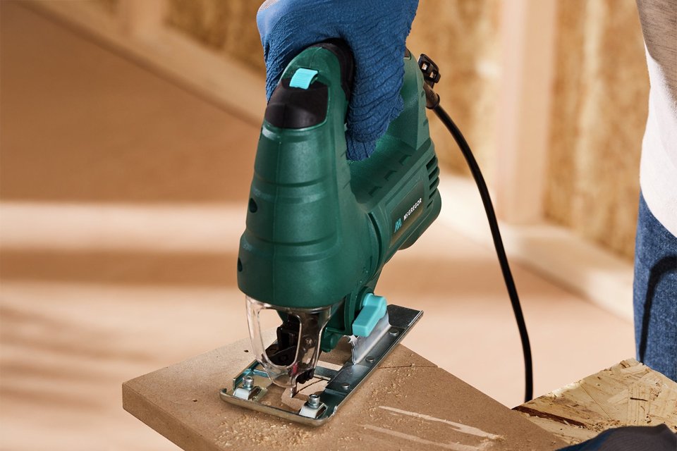 A man using a McGregor saw to carve a plank of wood.