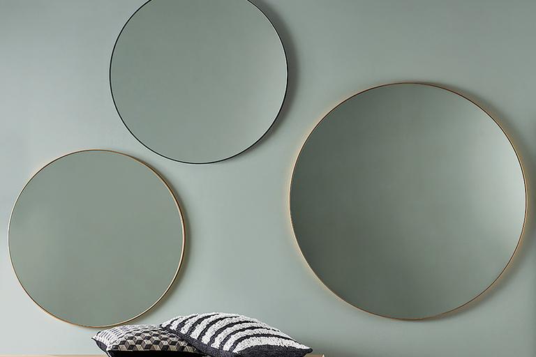 Three round mirrors hanging on the wall in brass and black.