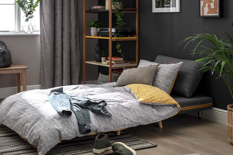 A charcoal double quilted sofa bed in a room.