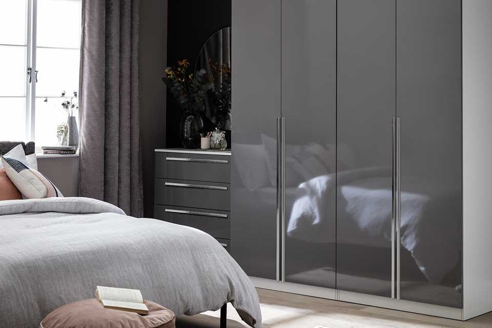 A four-drawerglossy grey wardrobe in a bedroom.