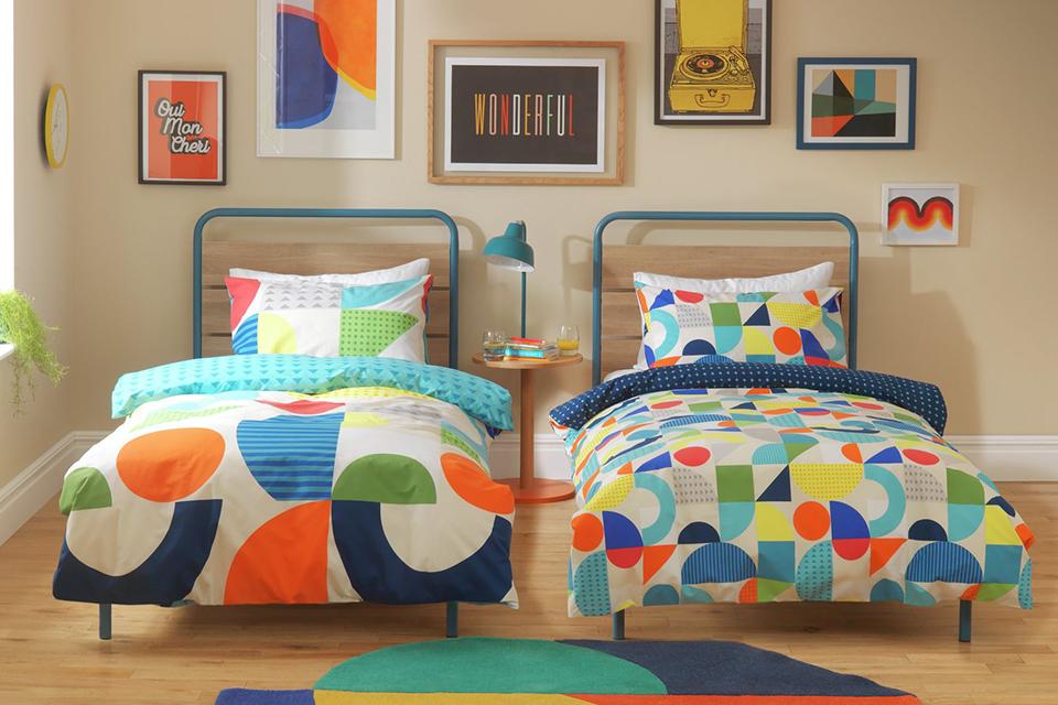 A colourful kids bedroom having two single beds with a geometric print on the bedding.