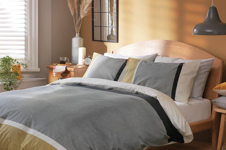 A grey and white duvet and pillows on a bed.