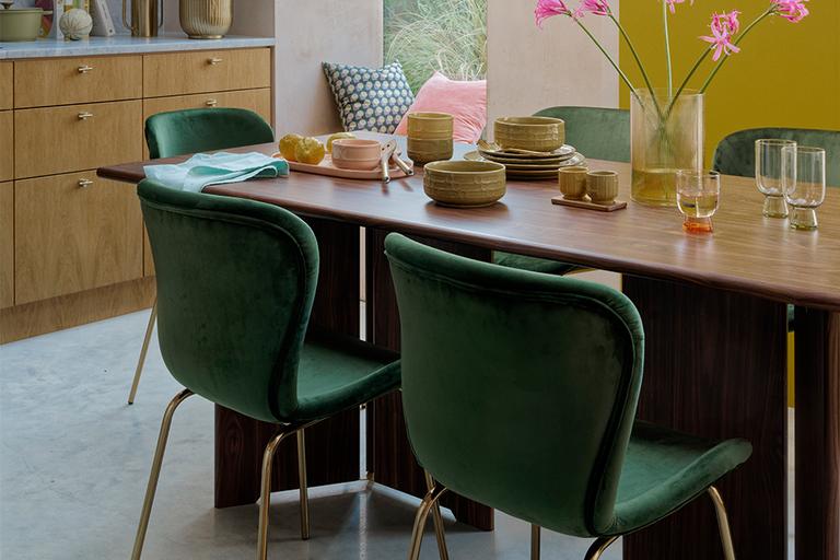 Wooden dining table with green velvet dining chairs.