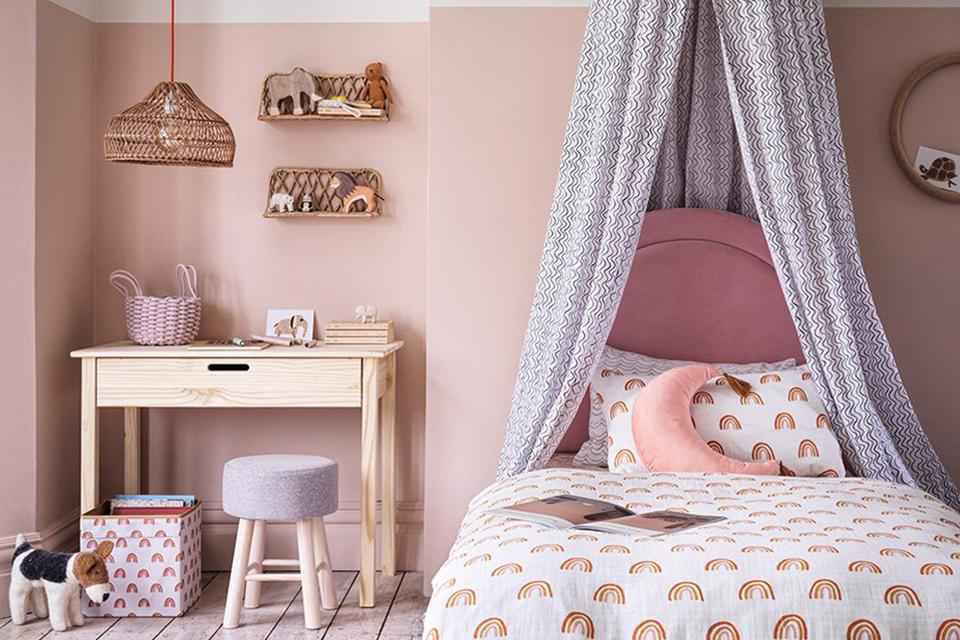 A kids bedroom in pink with a pink bed and natural finish study table.
