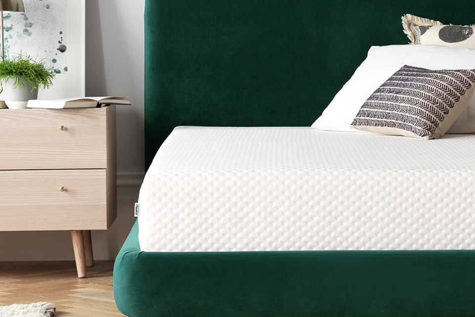 White mattress on green velvet headboard.
