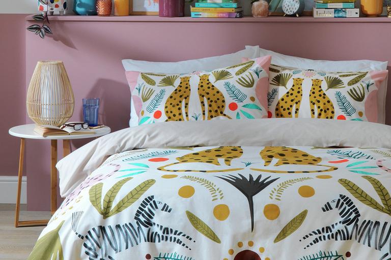 A mutilcoloured bedding with animal and natual element print in a pink bedroom.