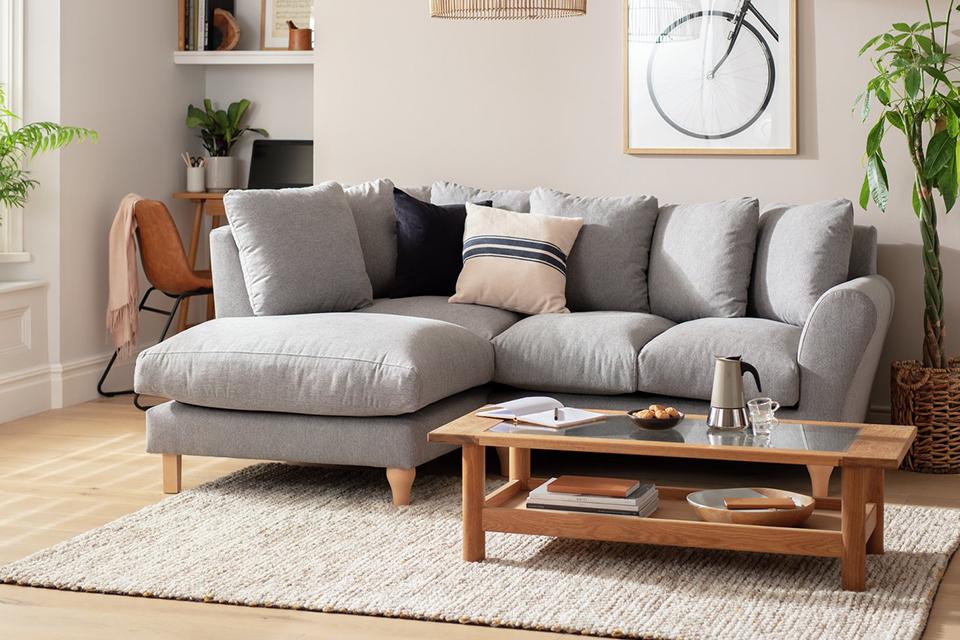 A living room with a L shaped grey sofa and wooden coffee table.