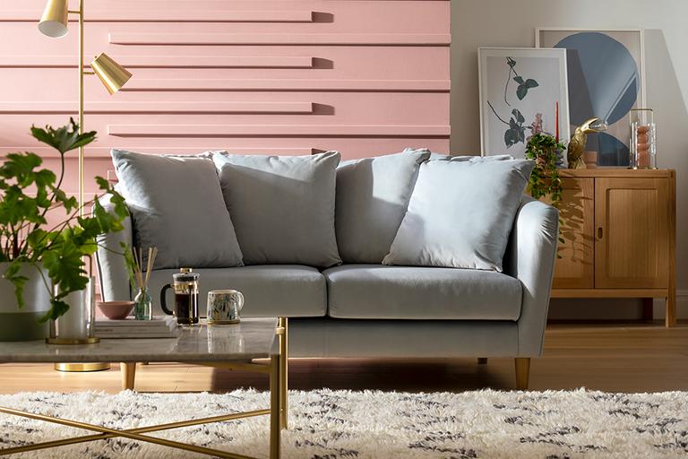 A modern living room with a comfy, grey sofa, a rug and coffee table.