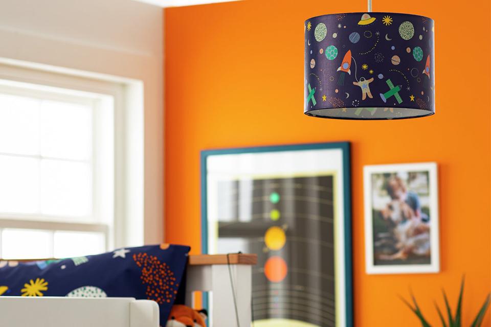 A space print ceiling lamp in an orange and white kids bedroom.
