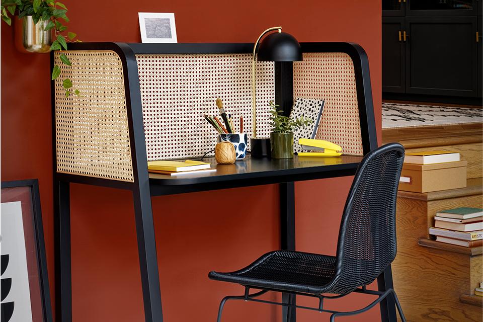 A black and beige work desk and chair in rattan effect.