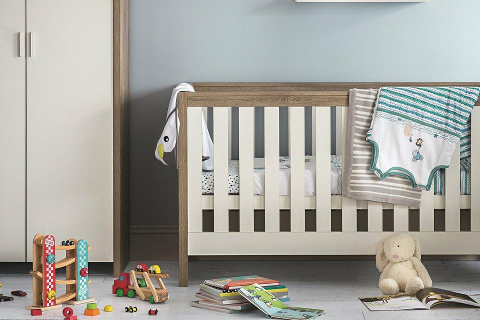 A white and oak cot bed in a blue colour kid's room.