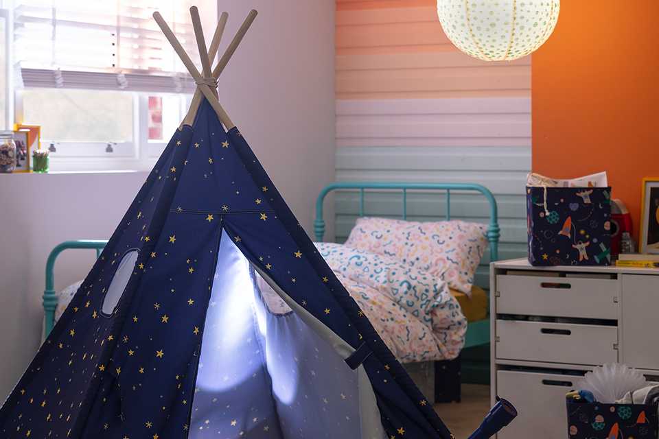A Habitat kids' navy blue space teepee tent in a bedroom.
