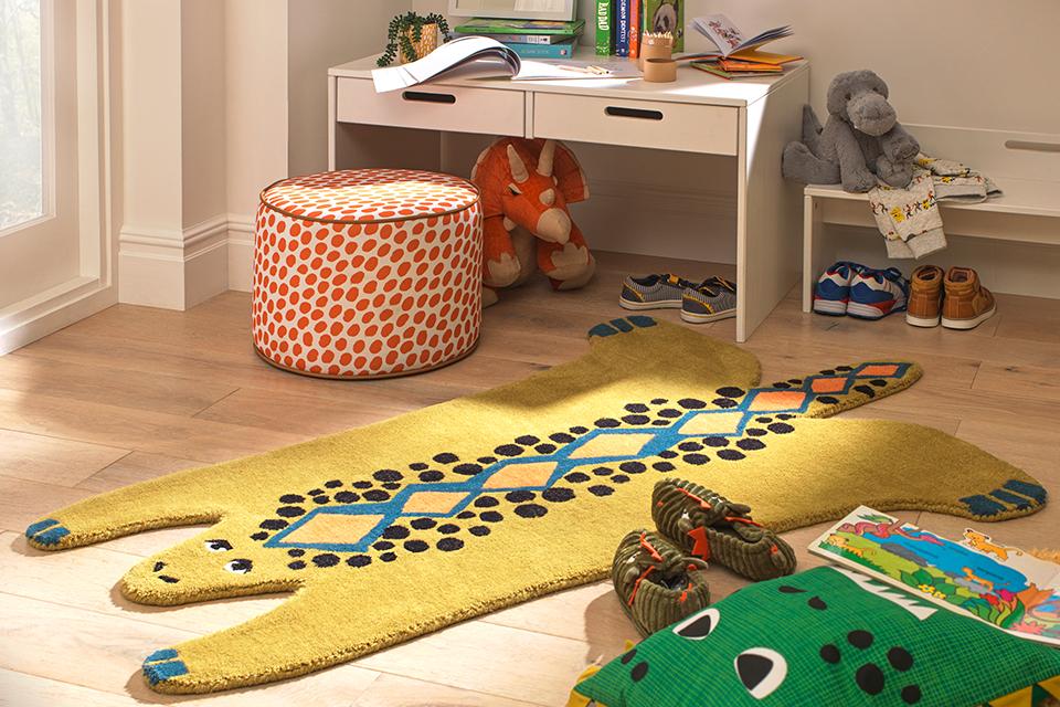 A yellow animal rug, pouffe and table in a kid's room.