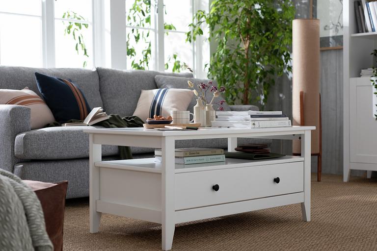 A white coffee table with storage space displayed in a living room with grey sofa.