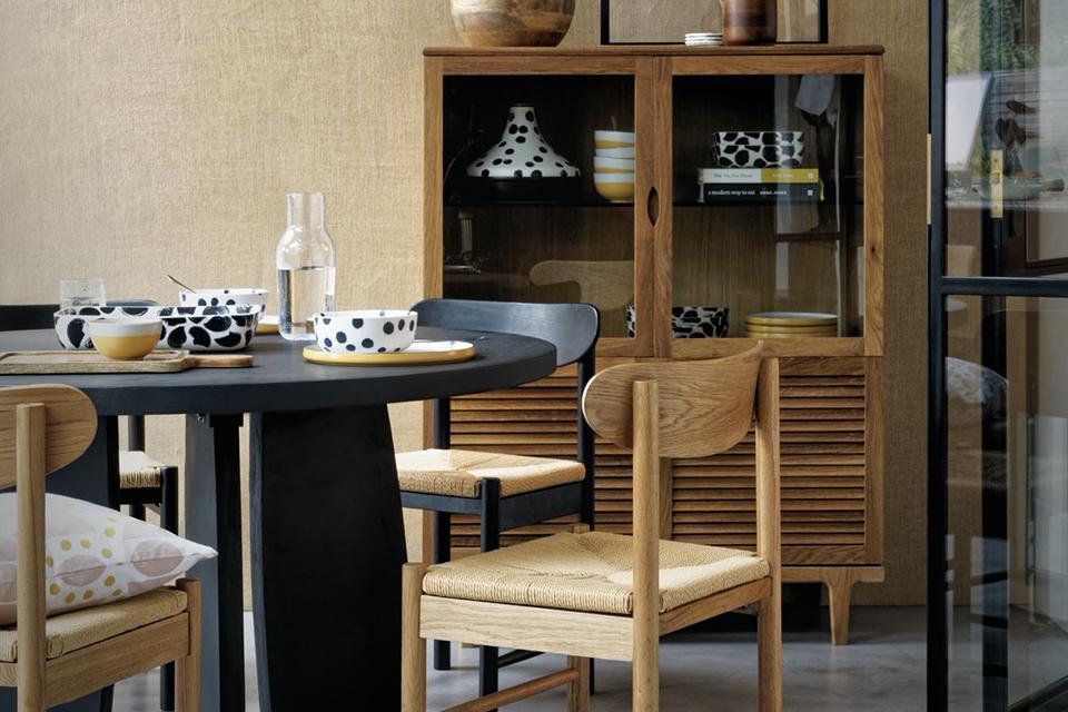 A dining room with a wooden shelf, hand-printed tableware and dining table set in black and wooden finish. 
