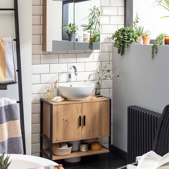 A bathroom with wooden and black framed cabinet, storage mirror and indoor plants on display.  