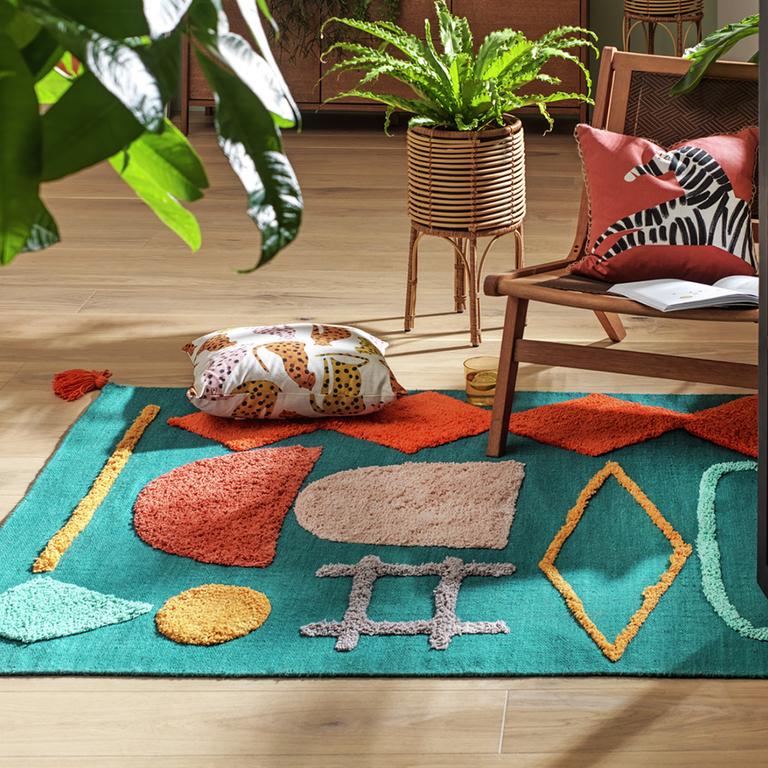 A bright and colourful woven rug with playful cushions on it.
