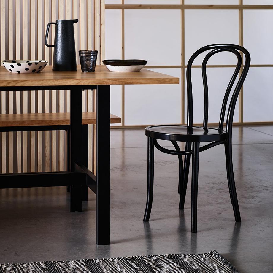 A modern country style dining room with a wooden dining table and black chair.
