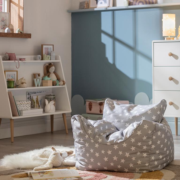 A grey and white star print beanbag in a grey kid's bedroom with white and natural finish furniture.