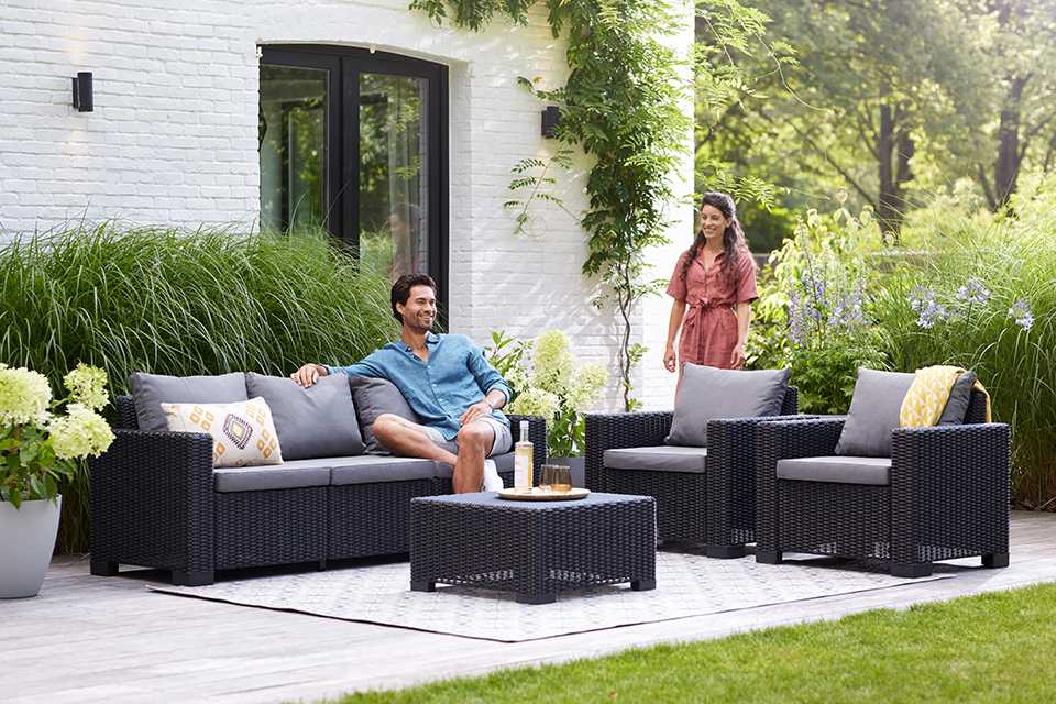 A couple relaxing outdoors on a Keter California 4-seater garden lounge set. 