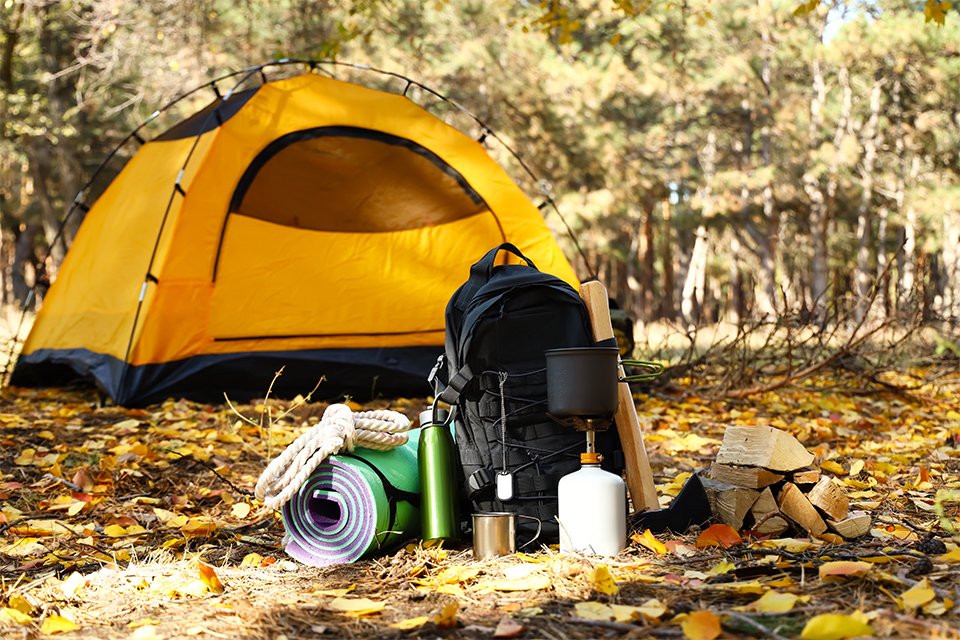 A small tent in the background with camping essentials outside 