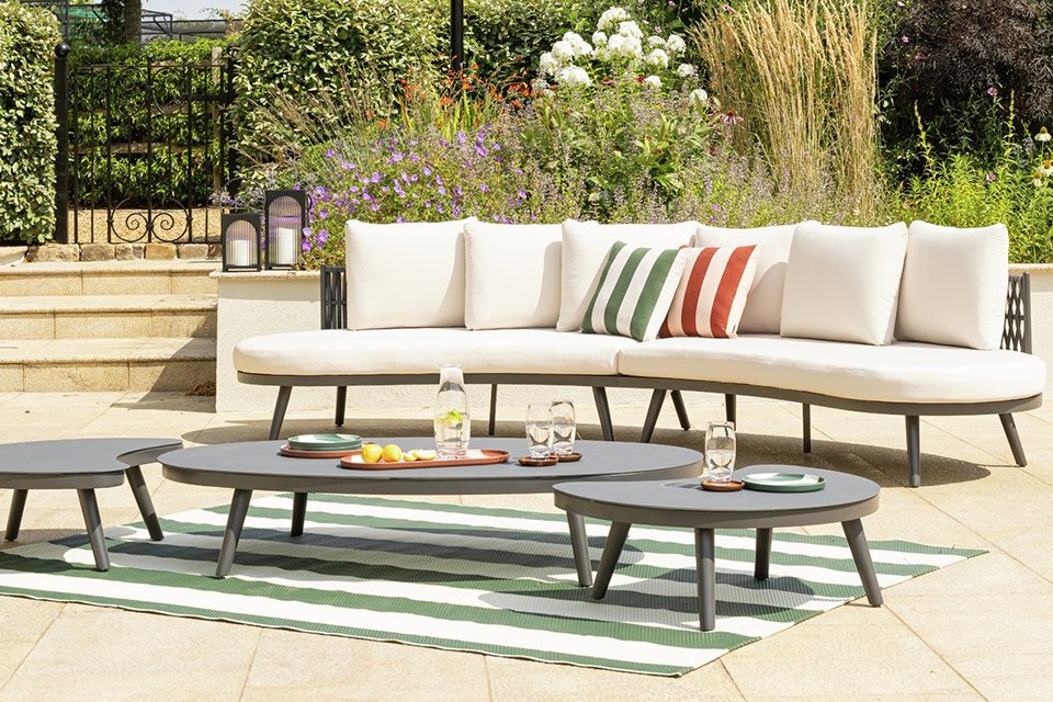 Habitat Santorini 6 Seater Rattan Effect Garden Sofa Set placed outdoors with cushions on it.