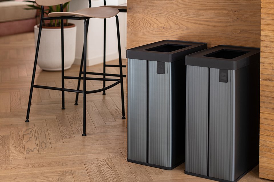 Two grey coloured Curver Verto recycling bin placed under a dining table.