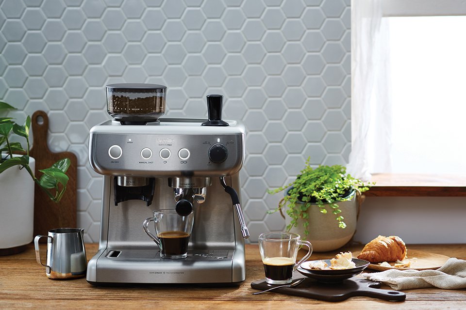 A silver Breville Barista Espresso coffee machine placed on a wooden kitchen countertop.