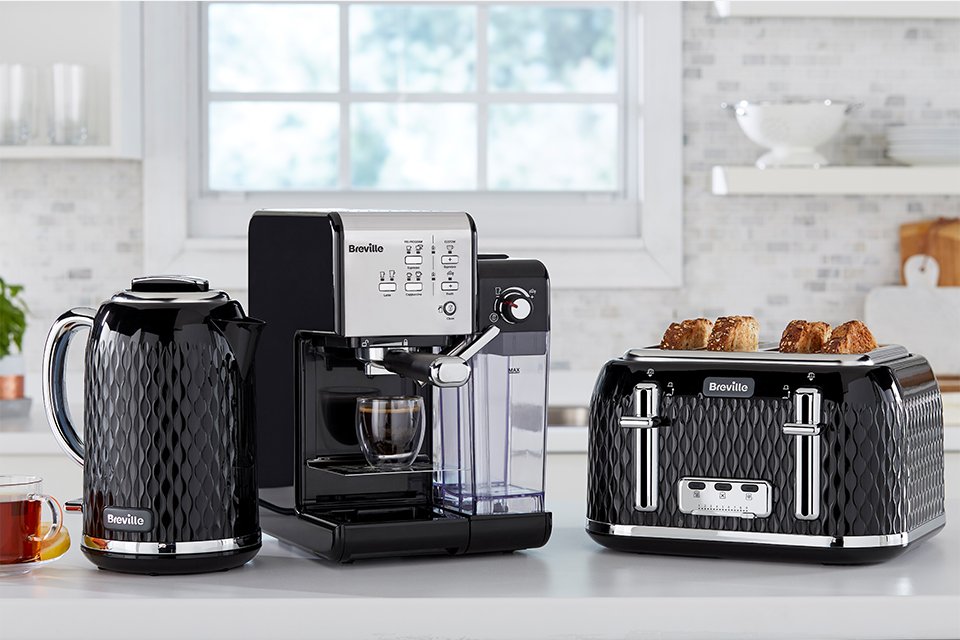 A black set of Breville toaster, coffee machine and kettle placed on a white kitchen countertop.