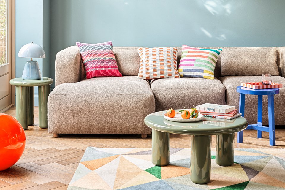 A Habitat cream coloured sofa placed in a living room with multicolour cushions on top of it.