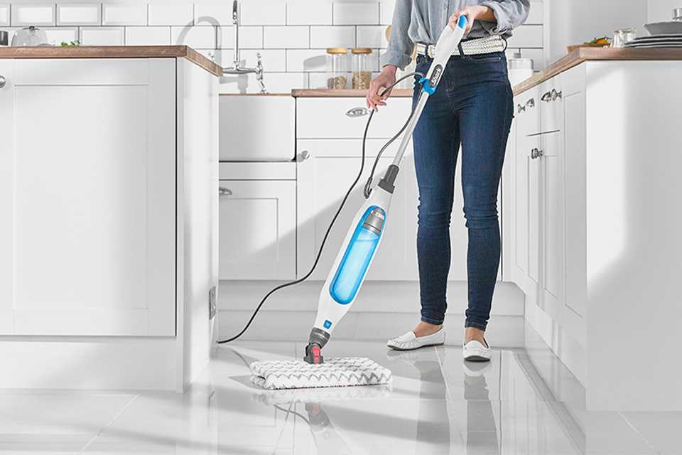 Lady cleaning a kitchen floor with a steam floor cleaner.