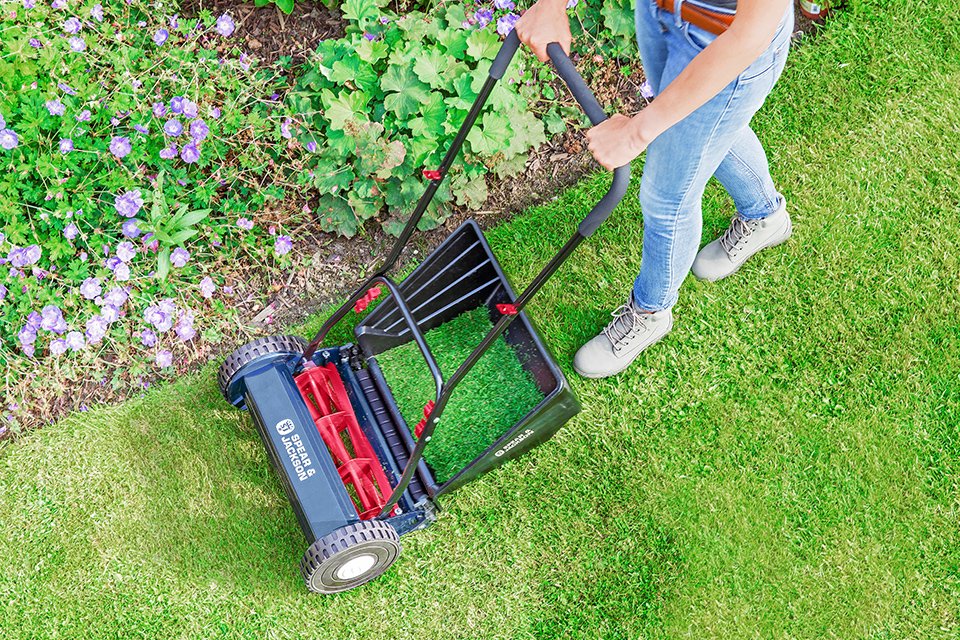  A person using Spear & Jackson 40cm Hand Push Cylinder Lawnmower on their lawn.