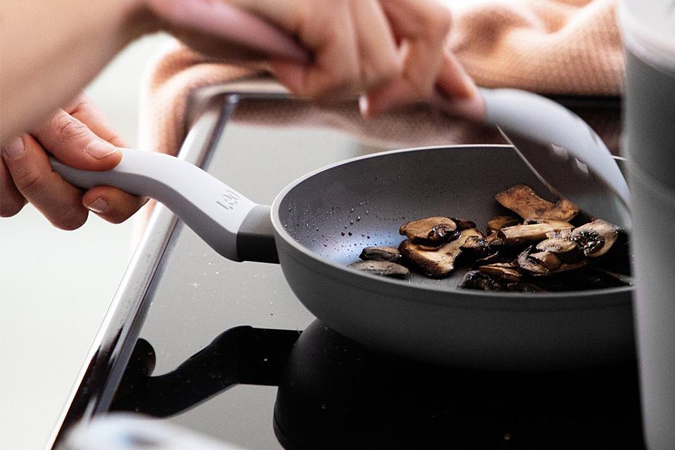 Image of someone cooking mushrooms in a frying pan.