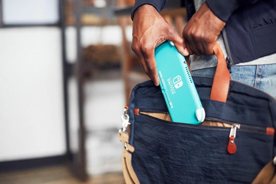 A man puts his Nintendo Switch Lite away in his bag.